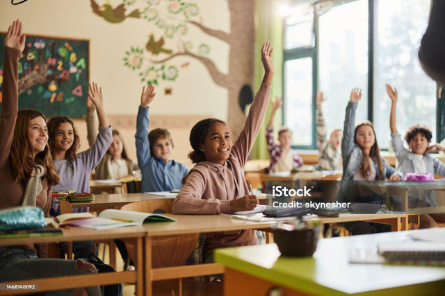 ''Foto ini menunjukkan suasana kelas yang ceria dan antusias belajar'' (Sumber: https://media.istockphoto.com/id/1410336912/id/foto/guru-dan-siswi-yang-bahagia-memberikan-tos-selama-kelas-di-sekolah.webp?s=612x612&w=is&k=20&c=qDywaLZLbXEoDs9925ZiYDWhokuv0XLVOu9kSjfhIHE=)