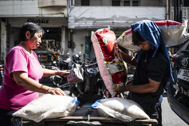 Pekerja (kanan) memindahkan karung beras ke atas sepeda motor di kawasan Pasar Dargo, Semarang, Jawa Tengah, Rabu (30/4/2025). Foto: Aprillio Akbar/ANTARA FOTO