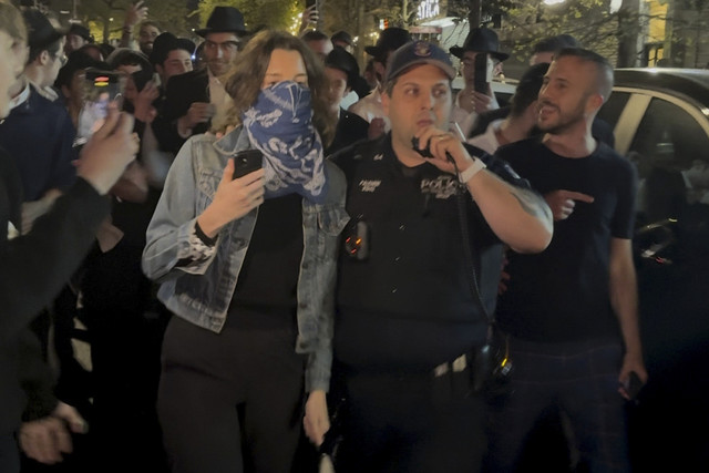 Gambar yang diambil dari video ini menunjukkan seorang wanita dan seorang petugas polisi saat mereka dikejar oleh gerombolan pria Yahudi Ortodoks di bagian Crown Heights di Brooklyn, N.Y., pada Kamis (24/4/2025). Foto: AP Photo
