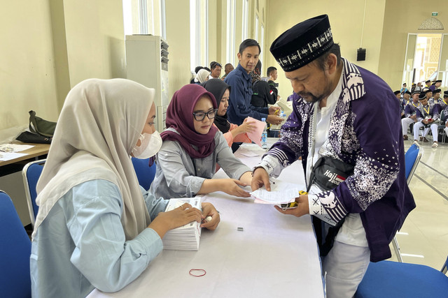 Petugas membantu jemaah calon haji asal Jawa Barat kelompok terbang (kloter) pertama saat tiba di Embarkasi Kertajati, Kabupaten Indramayu, Jawa Barat, Kamis (1/5/2025). Foto: kumparan