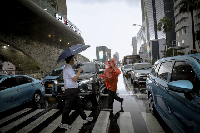 Beberapa orang berjalan di zebra cross menggunakan payung dan jas hujan di kawasan Bundaran HI, Jakarta, Rabu (7/5/2025). Foto: Jamal Ramadhan/kumparan