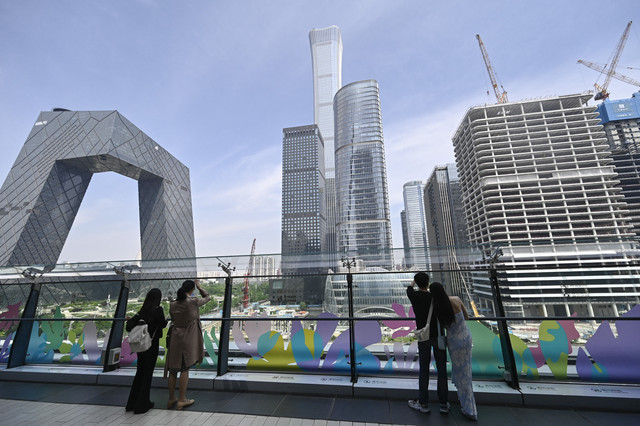 Sejumlah warga melihat gedung bertingkat di Beijing, China, Minggu (11/5/2025). Foto: Pedro Pardo/AFP