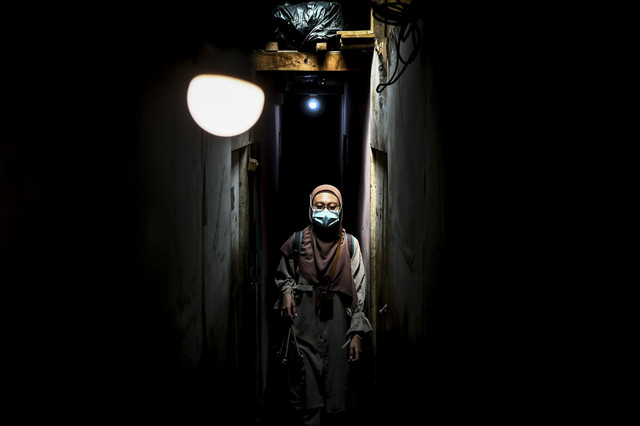 Melintasi Lorong Pemukiman Padat Penduduk: Perawat paliatif Tyas melintasi lorong permukiman padat penduduk usai memeriksa pasiennya di Jakarta. Foto: Rivan Awal Lingga/ANTARA FOTO