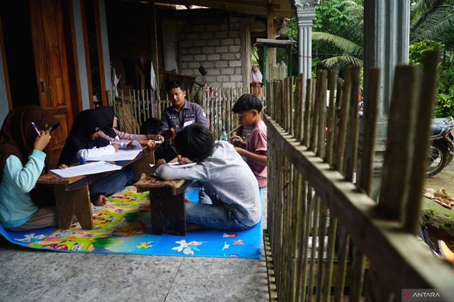 Lima siswa kelas 6 SDN 04 Depok, Trenggalek, mengikuti ujian sekolah di teras rumah warga akibat akses jalan ke sekolah mereka terputus total akibat bencana tanah longsor. Foto: ANTARA FOTO/Destyan Sujarwoko