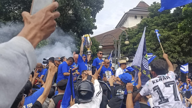 Momen saat Marc Klok pamerkan trofi juara Liga 1 musim 2024/2025 kepada Bobotoh saat pawai, Minggu (25/5/2025). Foto: Robby Bouceu/kumparan