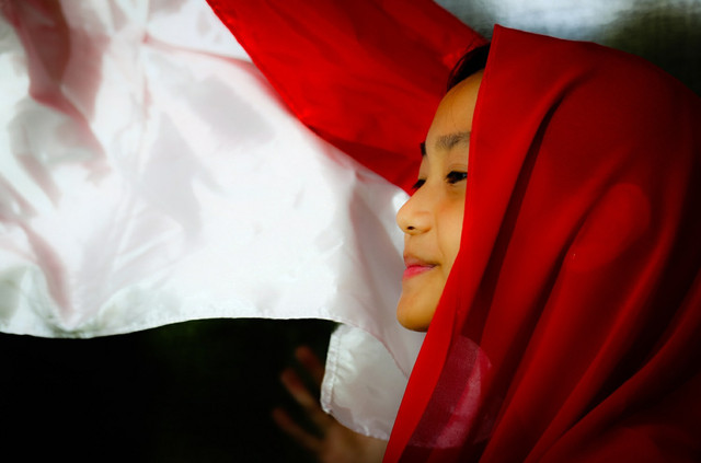 
Ilustrasi Gadis Dengan Latar Belakang Bendera Merah Putih. Sumber : Shutterstock.

