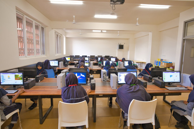Sekelompok siswi sedang belajar di laboratorium komputer sumber: https://unsplash.com/photos/a-group-of-people-sitting-at-desk-with-laptops-LKySOH0mr38