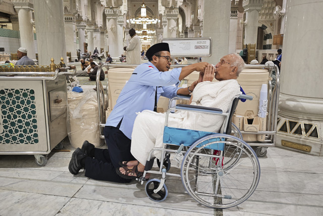 Petugas layanan lansia PPIH Arab Saudi Abdurrahman membantu meminumkan air zam zam kepada calon haji lansia Soemarno sebelum memulai rangkaian umrah wajib di Masjidil Haram. Foto: Andika Wahyu/ANTARA FOTO