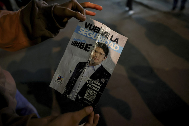 Seorang warga menunjukkan poster kampanye dilokasi penembakan senator Kolombia Miguel Uribe Turbay dari partai oposisi Democratic di Bogota, Kolombia, Sabtu (7/6/2025). Foto: Luisa Gonzalez/Reuters