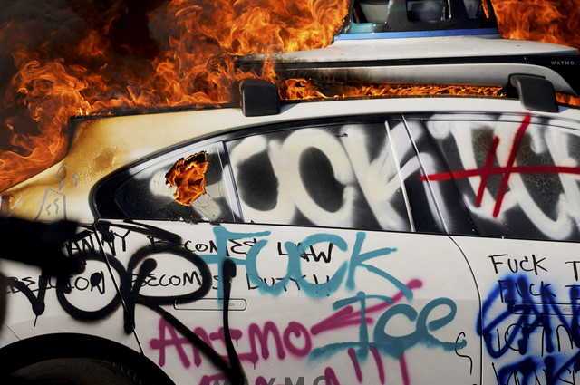 Sebuah mobil swakemudi Waymo terbakar dalam sebuah protes menentang razia imigrasi federal, di pusat kota Los Angeles, California, AS, Minggu (8/6/2025). Foto: David Ryder/REUTERS
