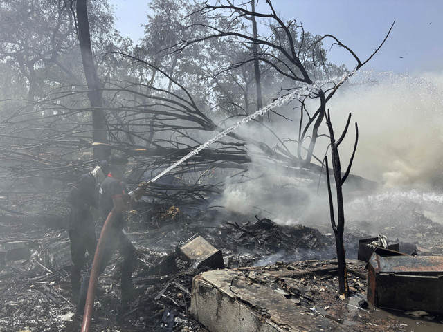 Petugas pemadam kebakaran bekerja di lokasi pesawat yang jatuh di kota Ahmedabad, negara bagian Gujarat, India barat laut, Kamis (12/6/2025). Foto: Ajit Solanki/AP Photo