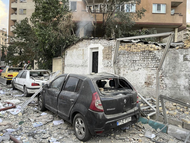 Puing-puing dari sebuah gedung apartemen terlihat di atas mobil-mobil yang diparkir setelah serangan di Teheran, Iran, Jumat (13/6/2025). Foto: Vahid Salemi/AP Photo