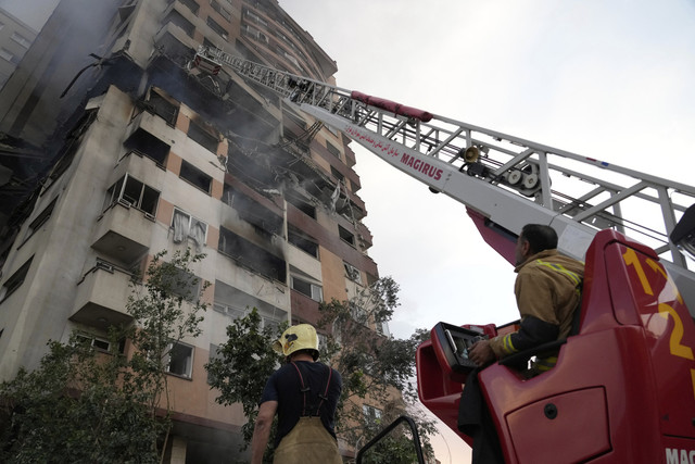 Petugas pemadam kebakaran bekerja di lokasi ledakan di sebuah kompleks perumahan di Teheran utara, Iran, Jumat (13/6/2025). Foto: Vahid Salemi/AP Photo