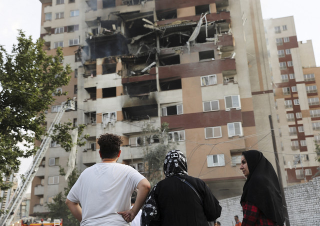 Orang-orang melihat sebuah bangunan yang rusak setelah serangan Israel, di Teheran, Iran, Jumat (13/6/2025). Foto: Majid Asgaripour / WANA / via REUTERS