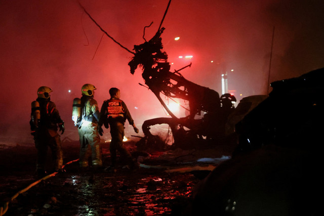 Petugas tanggap darurat meninjau bangunan yang hancur imbas serangan rudal Iran di Haifa, Israel, Minggu (15/6/2025). Foto: Shir Torem/REUTERS
