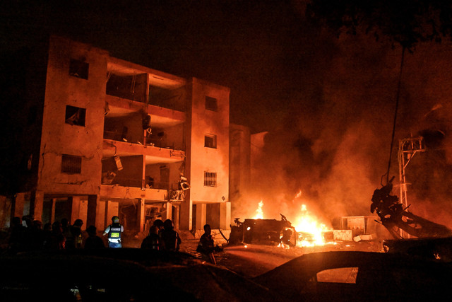 Petugas pemadam kebakaran dan petugas penyelamat meninjau lokasi usai serangan rudal Iran di Haifa, Israel, Minggu (15/6/2025). Foto: Rami Shlush/REUTERS