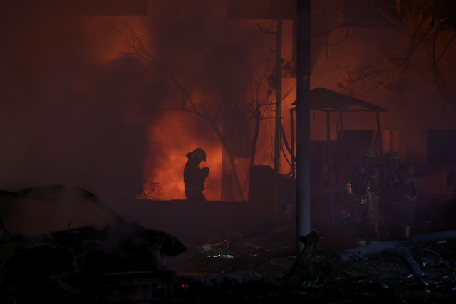 Petugas pemadam kebakaran bekerja di lokasi kejadian setelah serangan rudal dari Iran di Tel Aviv, Israel, Minggu (15/6/2025). Foto: Ronen Zvulun/REUTERS