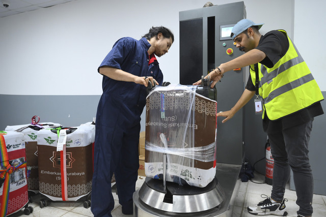 Petugas membungkus ulang koper bagasi jamaah haji Indonesia yang kedapatan membawa air zamzam setelah dipindai dengan mesin x-ray di salah satu lokasi penyortiran di Makkah, Arab Saudi, Senin (16/6/2025). Foto: Andika Wahyu/ANTARA FOTO
