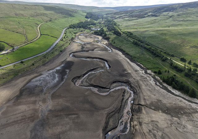 Foto udara kendaraan yang melaju di sepanjang jalan di sebelah bagian kering Waduk Woodhead setelah periode tanpa hujan dalam waktu yang lama membuat permukaan air turun di dekat Tintwistle, Inggris. Foto: Phil Noble/REUTERS