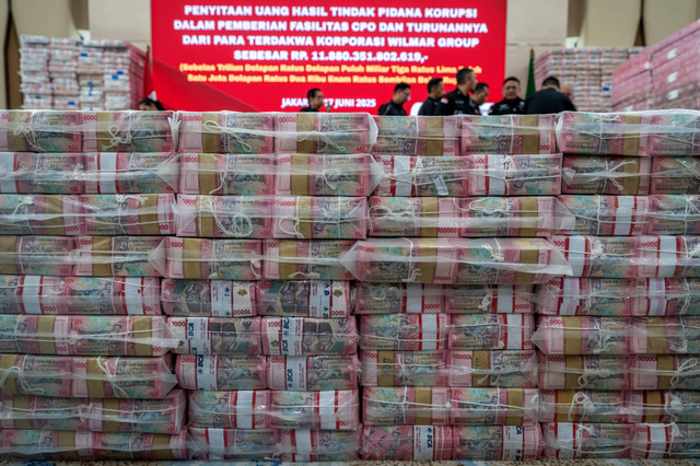 Petugas berada didekat barang bukti uang sitaan saat konferensi pers kasus korupsi ekspor crude palm oil (CPO) di Gedung Bundar Jampidsus Kejaksaaan Agung (Kejagung), Jakarta, Selasa (17/6/2025). Foto: Bayu Pratama S/ANTARA FOTO