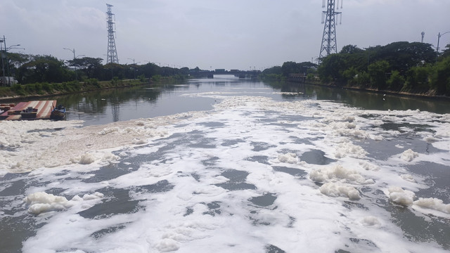 Gumpalan busa putih di kali BKT setelah keluar dari pintu air Wier 3 Marunda menuju Jembatan Pangkalan, Jakarta Utara, Senin (23/6/2025). Foto: Thomas Bosco/kumparan