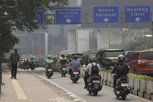 Seorang pekerja berjalan dengan mengenakan masker didekat kendaraan bermotor yang melintas di Jalan Sudirman, Jakarta, Kamis (26/6/2025). Foto: Jamal Ramadhan/kumparan