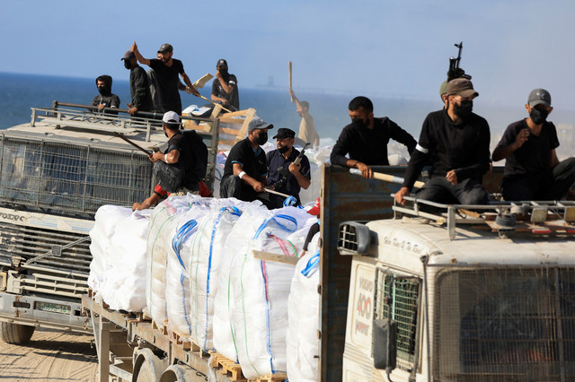 Warga Palestina dari berbagai klan memegang senjata untuk mengamankan truk bantuan di Beit Lahia, Jalur Gaza utara, Rabu (25/6/2025). Foto: Dawoud Abu Alkas/REUTERS