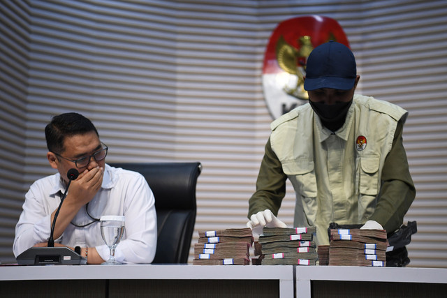 Plt Deputi Penindakan dan Eksekusi KPK Asep Guntur Rahayu (kiri) menyaksikan petugas KPK saat menunjukkan barang bukti uang yang disita dalam OTT kasus dugaan korupsi proyek pembangunan jalan di Dinas PUPR dan preservasi jalan di satuan PJN. Foto: ANTARA FOTO/Indrianto Eko Suwarso