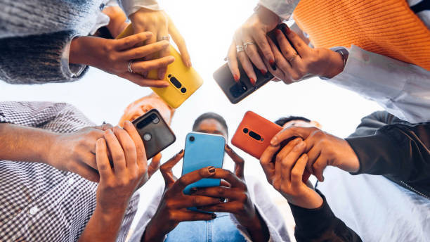 sekelompok anak muda yang sedang berdiri dan masing-masing memegang ponsel pintar (Smartphone). Sumber: Pixabay.com