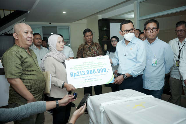 Menteri Pelindungan Pekerja Migran Indonesia, Abdul Kadir Karding (ketiga dari kanan) menyerahkan santunan Jaminan Sosial Ketenagakerjaan kepada keluarga setelah Ngadiman meninggal di Korea Selatan akibat kecelakaan kerja di Gateway Human Remains – Cargo Jenazah, Bandara Internasional Soekarno-Hatta pada Minggu petang (29/6). Foto: Dok. BPJS Ketenagakerjaan