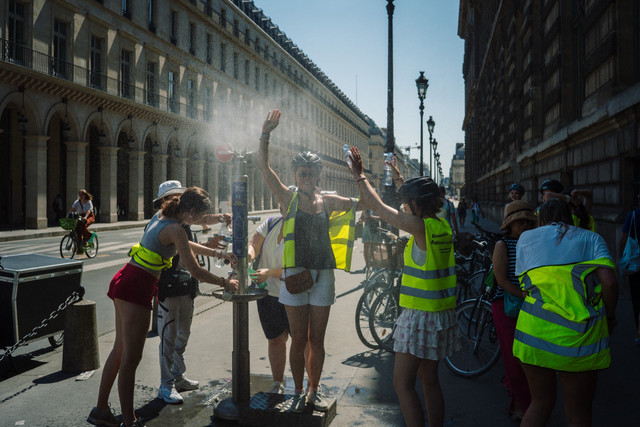 Para wisatawan mencoba menyejukkan diri di tempat pemandian air dekat museum Louvre di pusat kota Paris,. Foto: Dimitar DILKOFF / AFP