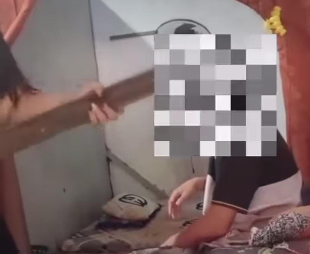Seorang pemuda hendak dipukul oleh wanita yang diduga terapis panti pijat menggunakan kayu karena korban tidak memiliki cukup uang untuk melunasi biaya jasa pijatnya. Foto : Potongan Video