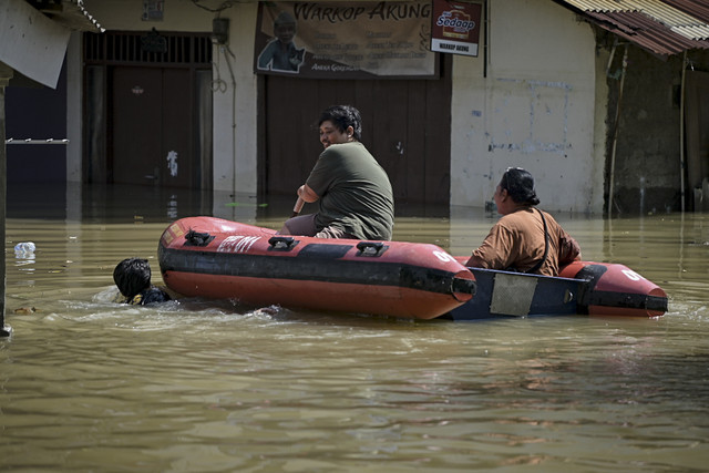 Dua warga menaiki perahu karet saat banjir di kawasan Bidaracina, Jatinegara, Jakarta Timur, Minggu (6/7/2025). Foto: Jamal Ramadhan/kumparan