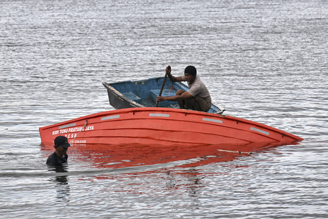 Petugas melihat sekoci yang ditemukan dalam operasi SAR tenggelamnya KMP Tunu Pratama Jaya di Gilimanuk, Jembrana, Bali, Sabtu (4/7/2025). Foto: Sonny Tumbelaka/AFP