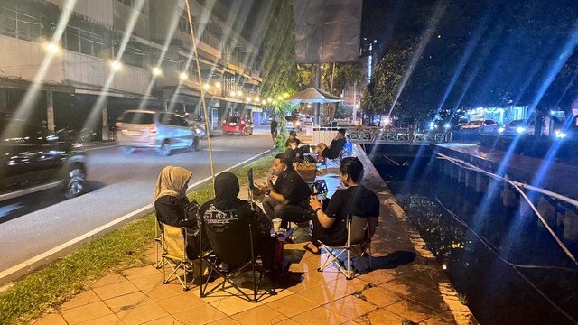 Pengunjung tampak bersantai menikmati kopi di pinggir jalan pada malam hari. Foto: Alycia Tracy Nabila/Hi!Pontianak