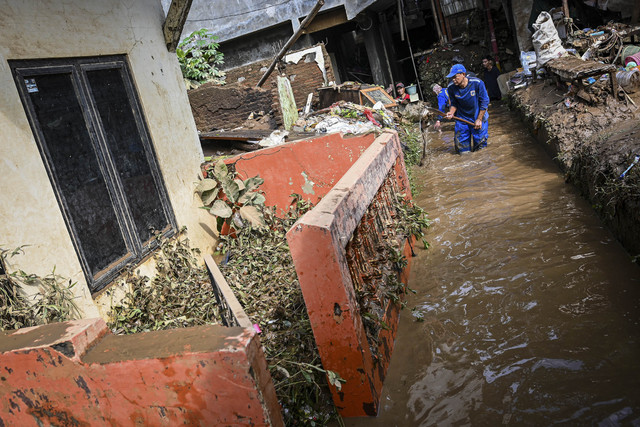 Petugas Dinas Sumber Daya Air membersihkan material banjir di kawasan permukiman di Kramat Jati, Cawang, Jakarta, Senin (7/7/2025). Foto: Sulthony Hasanuddin/ANTARA FOTO