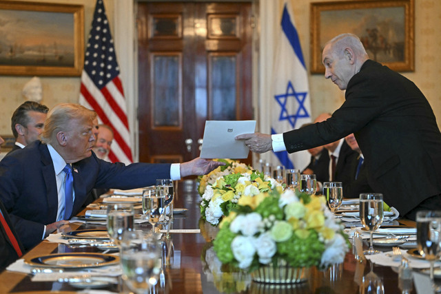 Perdana Menteri Israel Benjamin Netanyahu (Kanan) menyerahkan surat kepada Presiden AS Donald Trump saat mereka bertemu di Ruang Biru Gedung Putih di Washington, DC, Senin (7/7/2025) waktu setempat. Foto: Andrew Caballero-Reynolds/AFP