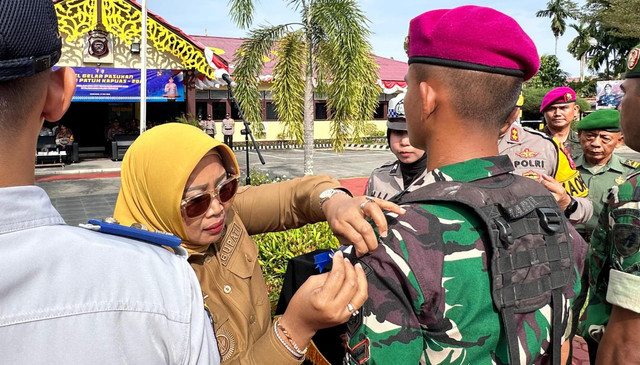 Bupati Erlina menyematkan pita kepada petugas saat apel gelar pasukan Operasi Patuh Kapuas 2025. Foto: M. Zain/Hi!Pontianak