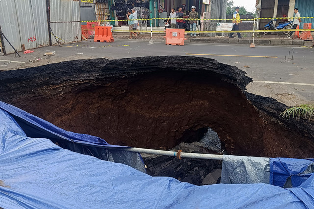Warga mengamati kondisi jalan amblas di jalur Denpasar-Gilimanuk, Desa Bajera, Tabanan, Bali, Selasa (8/7/2025).  Foto: Nyoman Hendra Wibowo/ANTARA FOTO