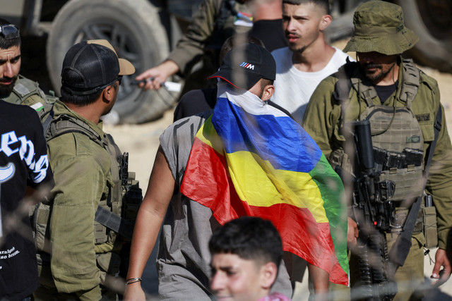 Seorang pria menutupi wajahnya dengan bendera Druze saat gencatan senjata antara Dataran Tinggi Golan yang diduduki Israel dan Suriah di kawasan Druze, Suriah, Sabtu (16/7/2025). Foto: Ammar Awad/Reuters