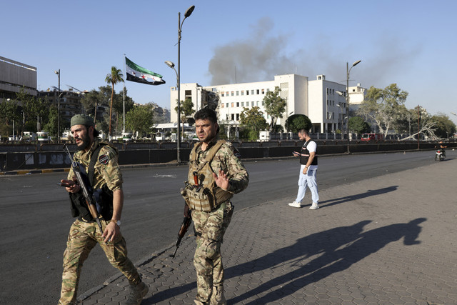 Anggota pasukan keamanan Suriah berjaga setelah serangan Israel ke markas tentara dan kementerian pertahanan Suriah di Damaskus, Suriah, Rabu (16/7/2025). Foto: Bakr Alkasem/AFP