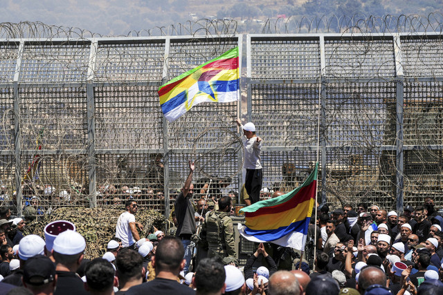 Seorang warga mengibarkan bendera Druze saat konflik berlangsung di Suriah, Rabu (16/7/2025). Foto: Ammar Awad/Reuters