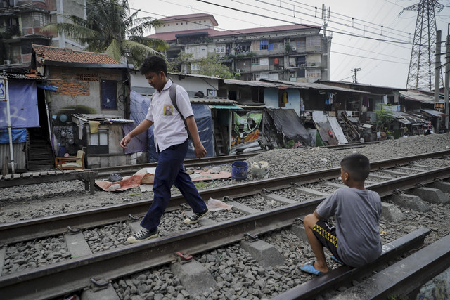 Dua warga beraktivitas di rel kereta api di kawasan Pejompongan, Jakarta, Kamis (16/7/2025). Foto: Jamal Ramadhan/kumparan