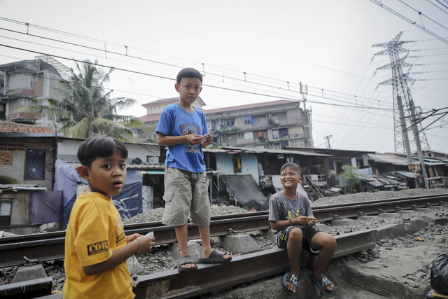Tiga bocah berbincang di rel kereta api di kawasan Pejompongan, Jakarta, Kamis (16/7/2025). Foto: Jamal Ramadhan/kumparan