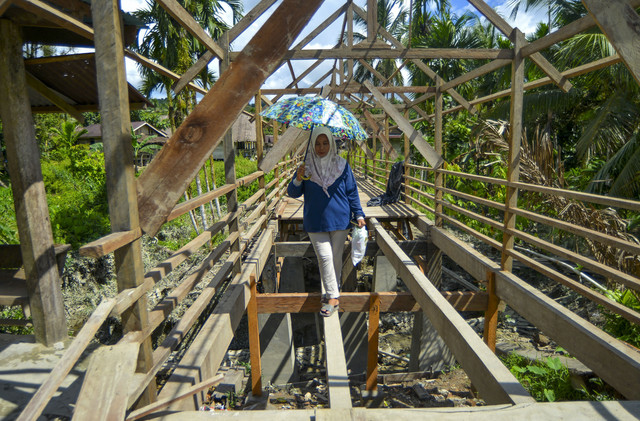 Berangkat untuk mengobati: Bidan Ilen, berjalan melewati jembatan yang belum jadi saat akan mengobati warga di Desa Matotonan, Siberut Selatan, Mentawai, Sumatera Barat. Foto: Iggoy el Fitra/ANTARA FOTO