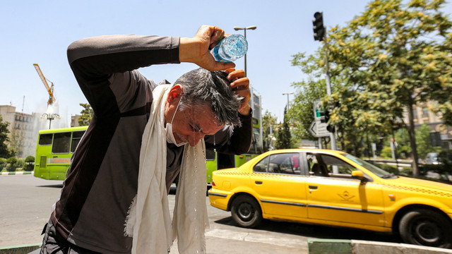 Seorang pria menuangkan air ke kepalanya dari botol untuk mendinginkan diri saat gelombang panas melanda Teheran pada 11 Juli 2023. Foto: ATTA KENARE / AFP