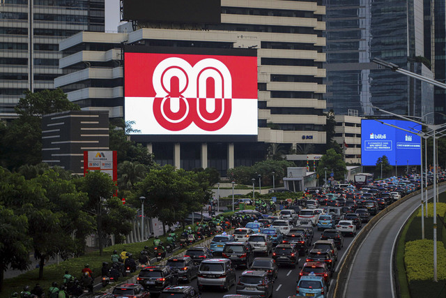 Sejumlah kendaraan melintas di dekat Videotron yang menampilkan logo HUT RI ke-80 di kawasan Jalan Sudirman, Jakarta, Kamis (24/7/2025). Foto: Iqbal Firdaus/kumparan