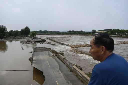 Seorang pria menatap jalan rusak di desa Taishitun, distrik Miyun, pinggiran Beijing pada Senin (28/7). Foto: Jade Gao/AFP