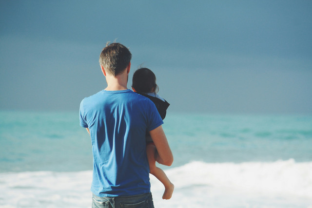 Potret seorang ayah sedang menggendong putrinya di sisi pantai. Foto: unsplash.com
