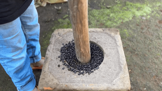 Petani Kopi sedang menumbuk hasil olahan kopi
